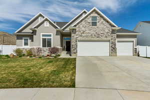 Craftsman-style home with fence, stone siding, and stucco siding