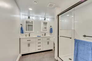 Bathroom with walk in shower, vanity, and tile patterned flooring