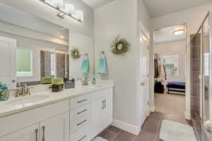 Bathroom with vanity, a shower with shower door, and tile patterned floors