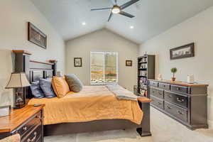 Carpeted bedroom with ceiling fan and lofted ceiling