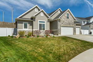 Craftsman-style house with driveway, fence, stone siding, and stucco siding