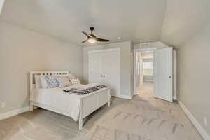 Bedroom featuring lofted ceiling, light colored carpet, ceiling fan, a textured ceiling, and a closet