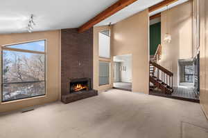 Living room featuring a brick fireplace, high vaulted ceiling, beamed ceiling, and carpet flooring