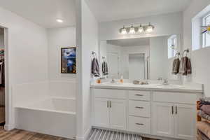 Bathroom featuring vanity, wood-type flooring, and a tub