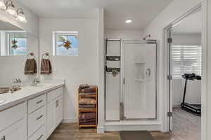 Bathroom with a shower with door, wood-type flooring, and vanity