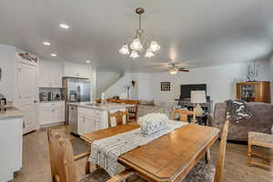 Dining space with sink, ceiling fan with notable chandelier, and light hardwood / wood-style flooring