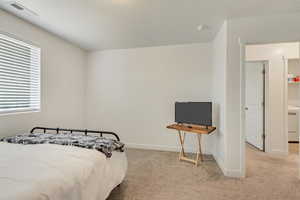 Bedroom with washer / dryer and light carpet