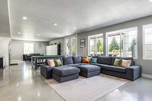 Living room with plenty of natural light, billiards, and a textured ceiling