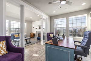 Office space with a fireplace, light hardwood / wood-style flooring, a textured ceiling, and ceiling fan