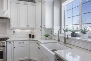 Kitchen featuring a wealth of natural light, sink, decorative backsplash, and white cabinets