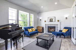 Sitting room featuring vaulted ceiling, a fireplace, and light hardwood / wood-style floors