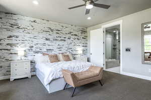 Bedroom featuring ceiling fan, ensuite bathroom, and dark carpet