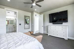 Carpeted bedroom featuring ceiling fan and ensuite bath