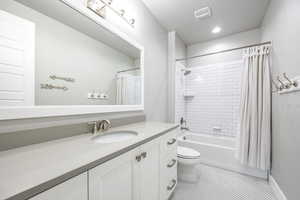 Full bathroom featuring vanity, a textured ceiling, tile patterned floors, toilet, and shower / bath combo with shower curtain