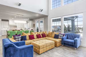 Living room with a towering ceiling, plenty of natural light, and light wood-type flooring