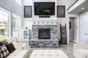 Living room with a fireplace, light wood-type flooring, and a high ceiling