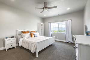 Bedroom featuring ceiling fan, dark carpet, and a textured ceiling