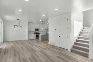 Unfurnished living room with sink and light hardwood / wood-style floors