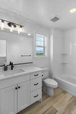 Full bathroom with vanity, wood-type flooring, shower / washtub combination, and toilet