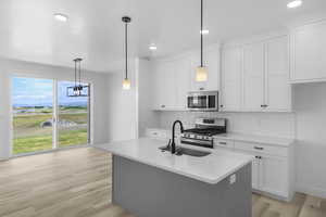 Kitchen featuring appliances with stainless steel finishes, sink, pendant lighting, and white cabinets