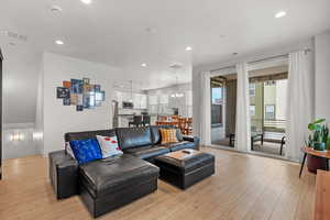 Living room with can lighting and laminate flooring opens to outdoor deck