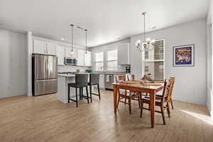 Dining area with an inviting chandelier, sink, and light laminate flooring