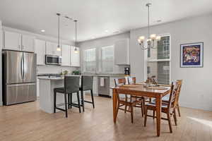 Large dining area featuring light laminate flooring, brushed nickel chandelier, and granite countertops