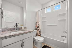 Full bathroom with vanity, granite countertops, toilet, and shower / bath combo