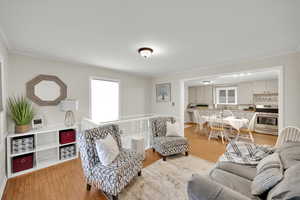 Living room with crown molding and light hardwood / wood-style flooring