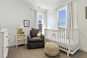 Carpeted bedroom featuring a crib