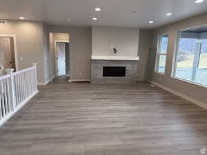 Unfurnished living room with a stone fireplace and light hardwood / wood-style floors