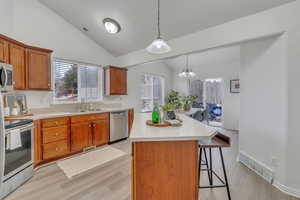 Kitchen featuring sink, a breakfast bar area, a center island, appliances with stainless steel finishes, and pendant lighting