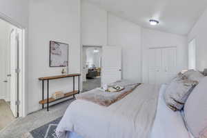 Bedroom featuring high vaulted ceiling, light colored carpet, and a closet