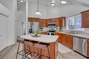 Kitchen featuring sink, a breakfast bar area, appliances with stainless steel finishes, hanging light fixtures, and a center island