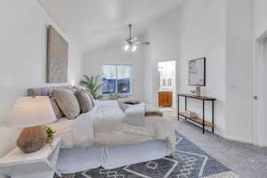 Carpeted bedroom featuring ensuite bathroom, ceiling fan, and high vaulted ceiling