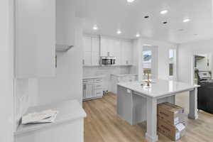 Kitchen with white cabinetry, sink, an island with sink, and light wood-type flooring