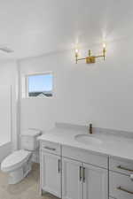 Bathroom featuring tile patterned flooring, vanity, a bathtub, and toilet