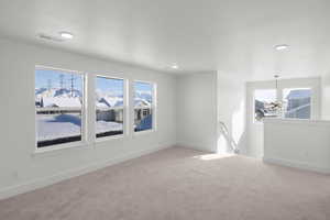 Carpeted empty room featuring an inviting chandelier