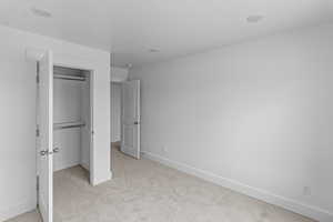 Unfurnished bedroom with light carpet and a closet