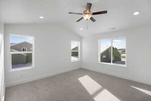 Empty room featuring ceiling fan, vaulted ceiling, and light carpet