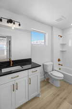 Full bathroom with hardwood / wood-style flooring, vanity, shower / washtub combination, and toilet