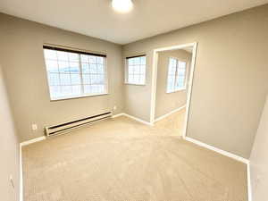 Spare room featuring baseboard heating and light colored carpet