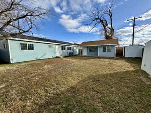 Back of property featuring a yard and an outbuilding