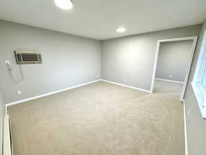 Interior space featuring light carpet and a wall unit AC