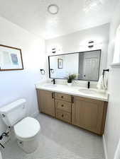 Bathroom featuring vanity, toilet, and a textured ceiling