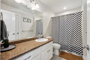 Bathroom featuring vanity, tile patterned floors, toilet, and walk in shower