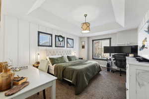 Bedroom featuring dark colored carpet and a tray ceiling