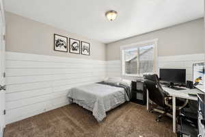 Bedroom featuring wood walls, a textured ceiling, and dark colored carpet