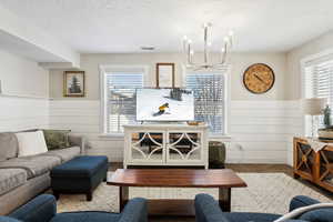 Carpeted living room with an inviting chandelier and a textured ceiling