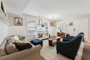 Living room featuring wood walls, a textured ceiling, and light wood-type flooring